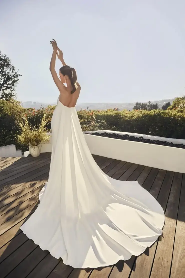 Model is wearing a strapless fit and flare wedding dress with a plunging neckline