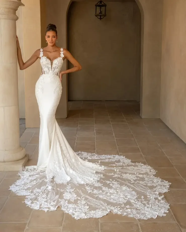 Model is wearing a fitted wedding dress with plunging neckline and lace straps by kitty chen