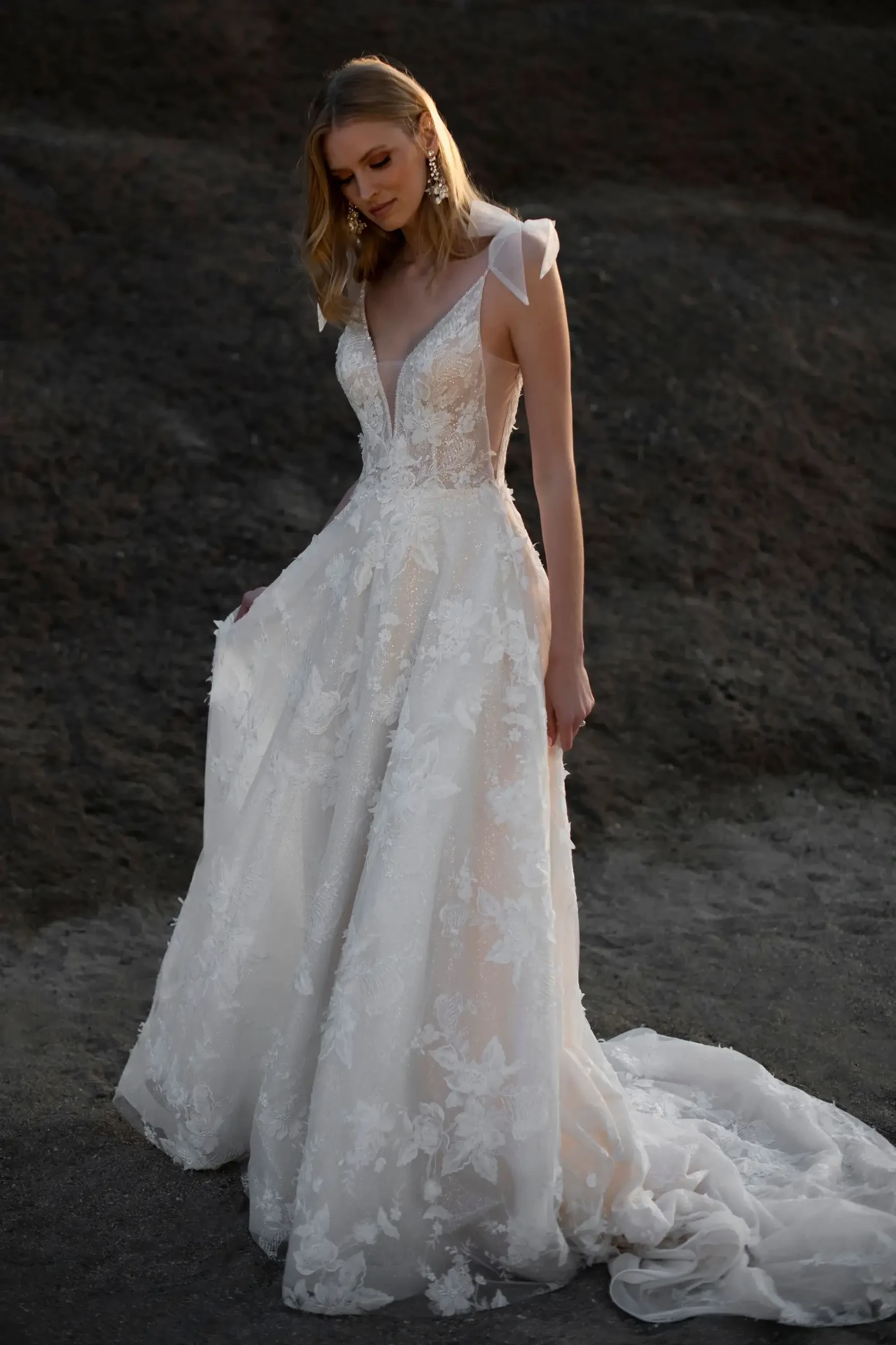 model is wearing a sleeveless a-line wedding dress with bow details on the straps