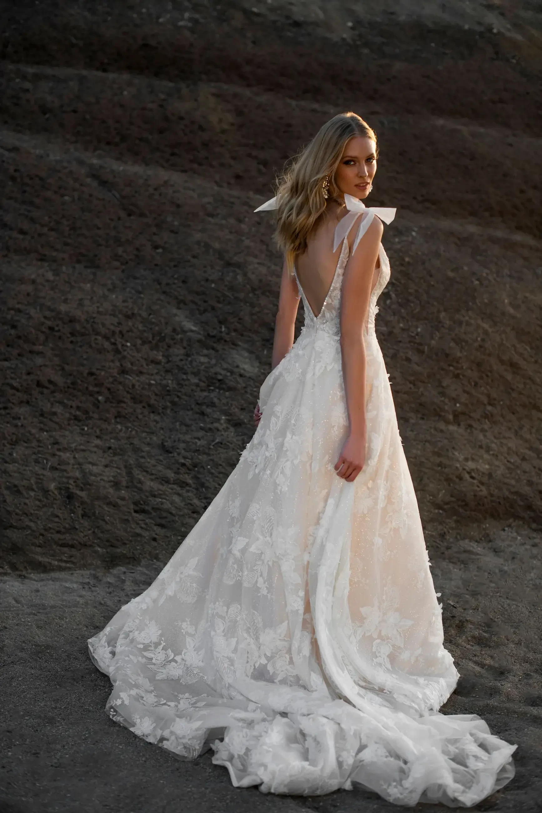 model is wearing a sleeveless a-line wedding dress with bow details on the straps