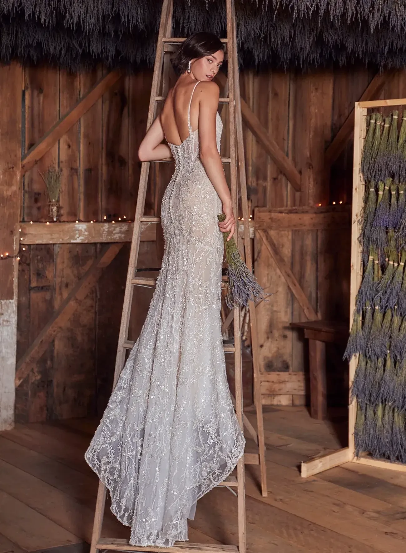 model is wearing a sleeveless beaded sheath bridal gown