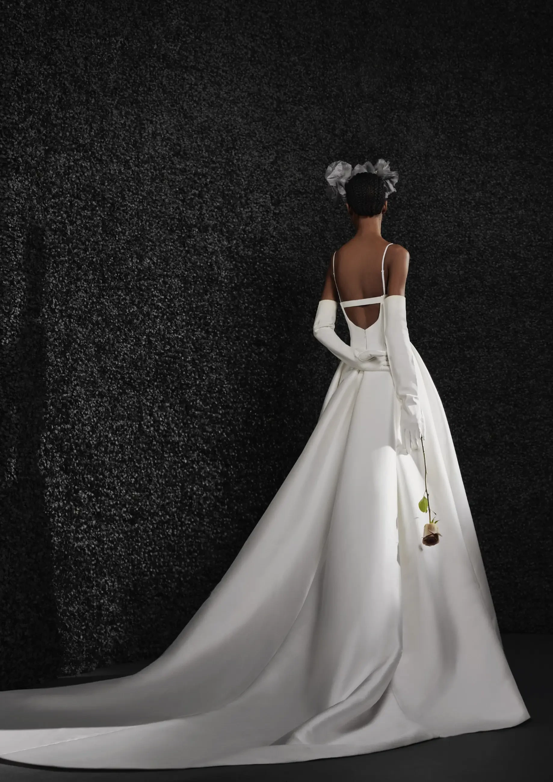 Model is wearing an ivory mikado A-line gown with a corset bodice, scoop back, box-pleated skirt, and detachable straps.