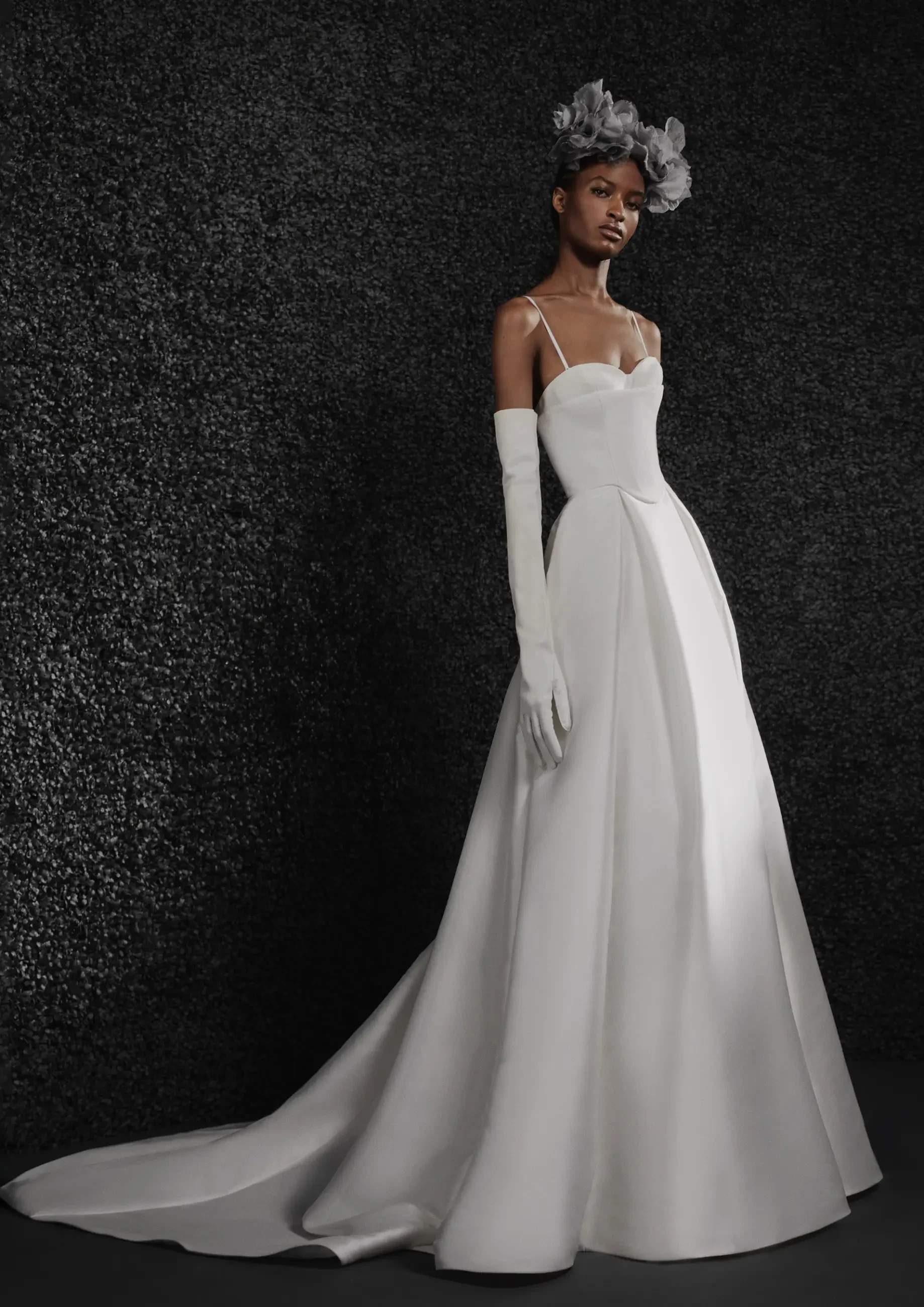 Model is wearing an ivory mikado A-line gown with a corset bodice, scoop back, box-pleated skirt, and detachable straps.